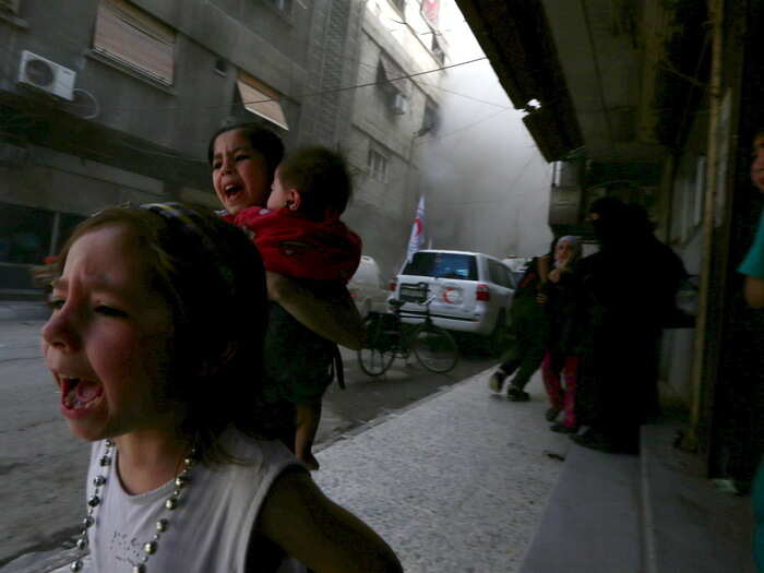 Ghazal, 4 years old, (L) and Judy, 7 years old and carrying 8-month-old Suhair, react to the destruction around them after what activists told Reuters was a shelling by President Bashar al-Assad