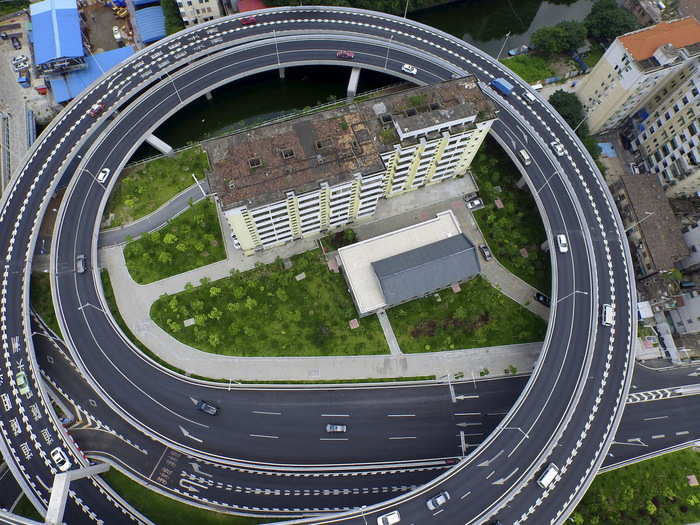 An old residential building is surrounded by a newly built ring viaduct in Guangzhou, China.