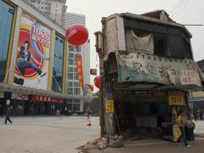 The last house in this area stands in front of a shopping mall in central China