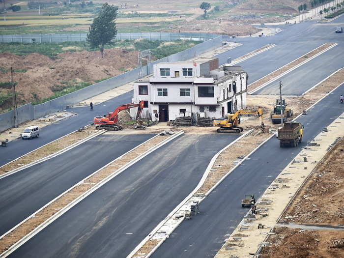 A three-story nail house with a Chinese national flag on its rooftop is seen in the middle of a newly-built road in the Henan province.