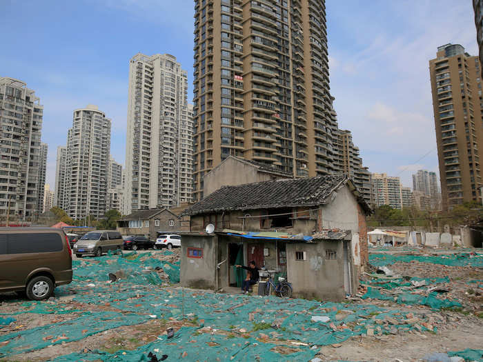 Residents of the Guangfuli area of Shanghai have collectively decided not to leave their homes, creating an entire nail neighborhood. Tao Weiren sits in front of his two-story house there, which is now surrounded by high-end condominium buildings.