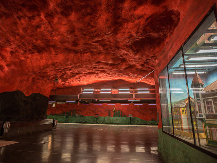 The Solna metro station is painted bright red and black. The black gradually lightens into a pastel green, which eventually reveals itself as the backdrop for an evergreen forest.