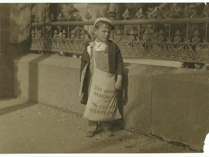 Freddie Kafer, a very immature little newsie selling Saturday Evening Posts and newspapers at the entrance to the State Capitol. He did not know his age, nor much of anything else. He was said to be 5 or 6 years old. Nearby, Hine found Jack who said he was 8 years old, and who was carrying a bag full of Saturday Evening Posts, which weighed nearly 1/2 of his own weight. The bag weighed 24 pounds, and he weighed only 55 pounds. He carried this bag for several blocks to the car. Said he was taking them home. Sacramento, California, May 1915.