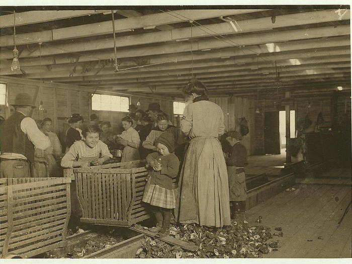 Four-year-old Mary, who shucks two pots of oysters a day and tends the baby when not working. The boss said that next year Mary will work steady as the rest of them. The mother is the fastest shucker in the place. She earns $1.50 a day. Works part of the time with her sick baby in her arms. Dunbar, Louisiana, March 1911.