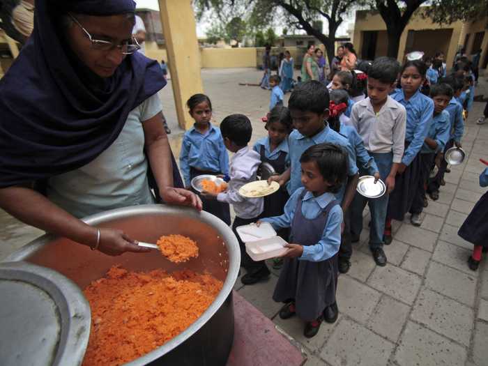 JAMMU, INDIA: Children stand in line to receive a free mid-day meal made of sweetened rice at a government school.