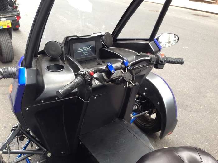 There are basic motorcycle handlebars, a single information screen — and a cupholder!