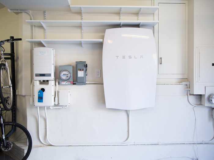 A Tesla Powerwall battery hangs in the garage. It charges using electricity generated from the solar panels and powers the home through the evening when the sun is gone.