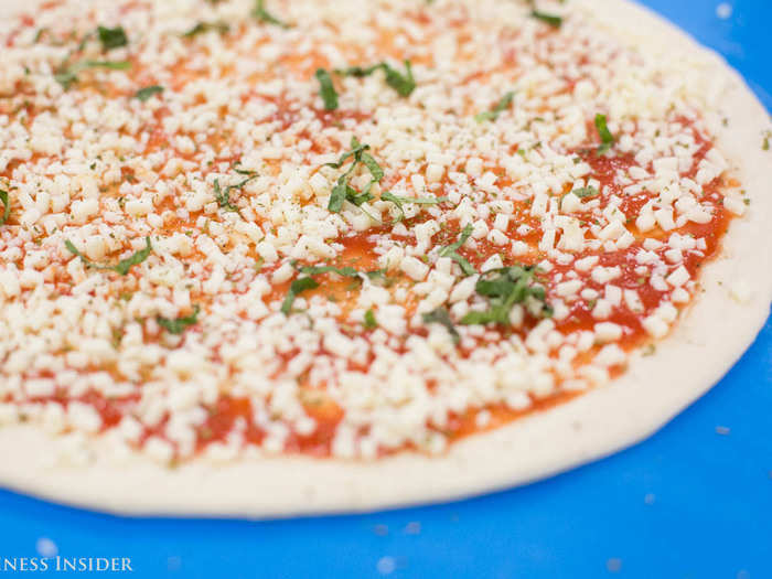 A human dresses the pie with cheeses and toppings, because as Collins puts it, "humans are good at doing toppings already."