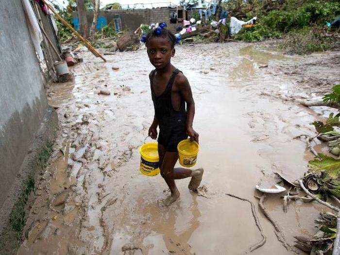 A girl lugs buckets of drinking water after the passing of Hurricane Matthew in Les Cayes.