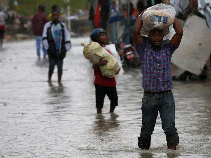 People carry their belongings through flooded streets.