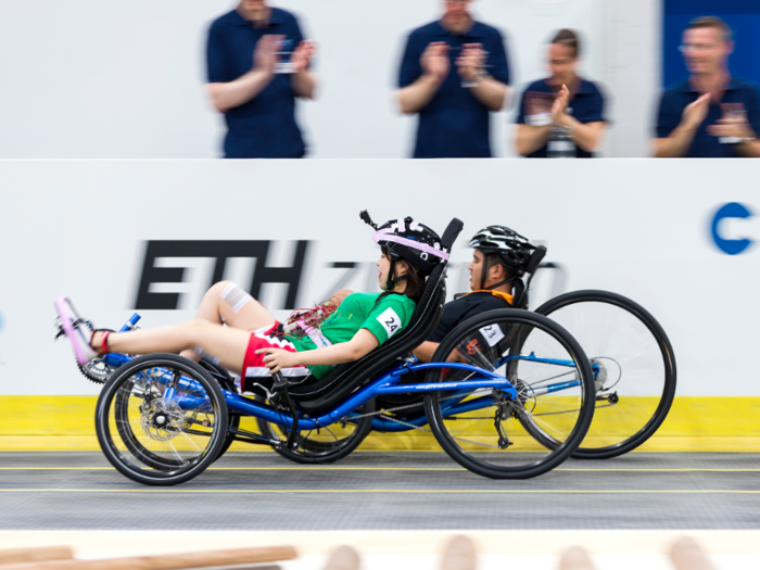 At first, the Muscle-Stimulated Bike Race might look like a Paralympic event, but the bikes are actually powered by electrical impulses in the athletes