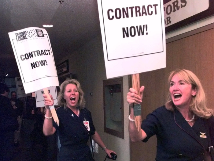 On August 26, 1999, two flight attendants carry signs out of a meeting room after rejecting a tentative five-year contract with Northwest Airlines.