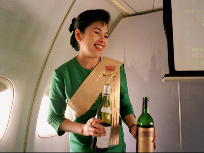 A Thai Airways International airline flight attendant presents a selection of wine during a flight from Singapore to Bangkok in 1996.