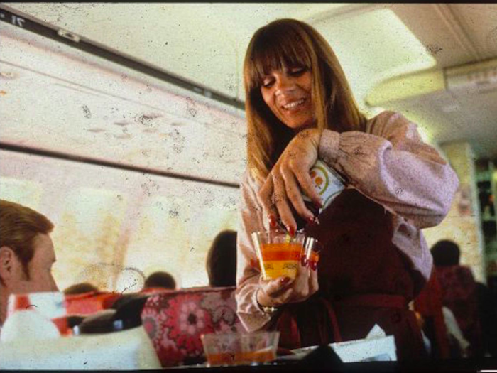 A PSA Airlines stewardess pours a drink for a passenger.