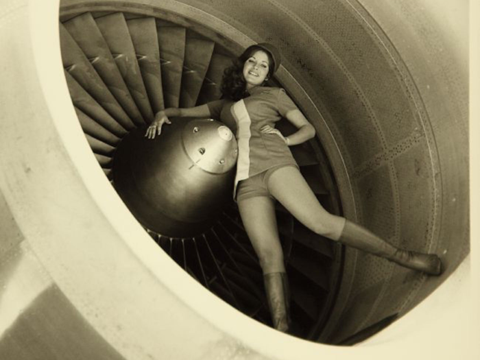 A flight attendant poses in front of a turbine.