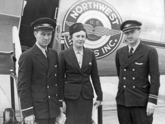 A flight attendant and two pilots pose outside of an aircraft. The image comes from an album belonging to Charles rector, a pilot who worked in Hollywood and flew for Mick Jagger.