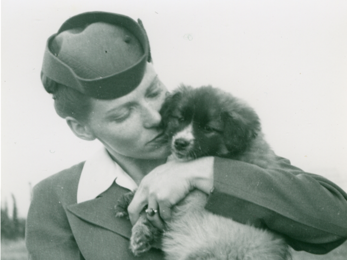 An airplane stewardess hugs a puppy in Alaska in the 1950s.