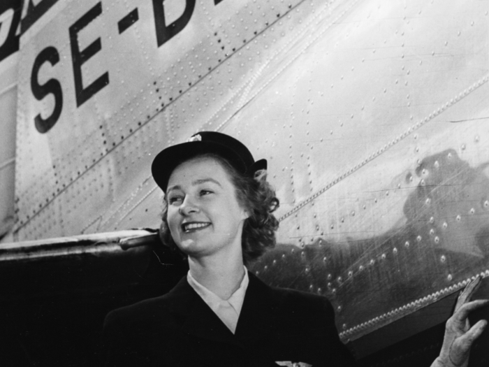 Flight attendant Britt Hansson smiles in front of a "Orvar Viking" aircraft in the late 1940s or early 1950s.