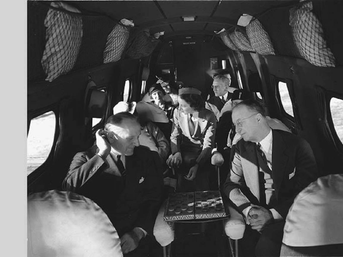 A flight attendant checks in with passengers as two men play checkers during a 1933 flight on a Boeing 247.