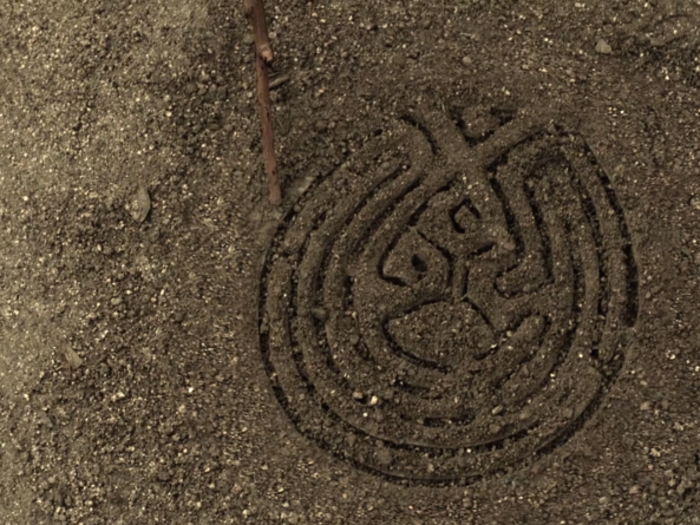 The young girl taps her stick on the dirt, and Dolores looks down to see the maze pattern.