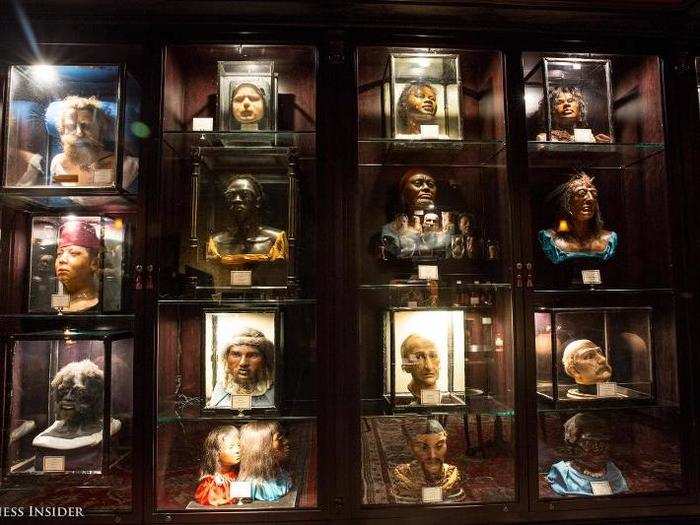 The bar exhibits a curated selection of rare German waxwork sculptures including life-size displays of human oddities, animal attractions, and death masks.