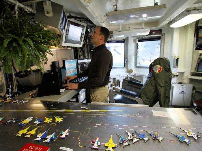 Going up, the way to the deck passes through flight deck control where the old-school "Ouija board" is used to keep track of the confusion outside.