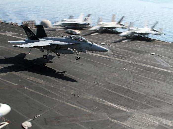 Tail hooks down, the pilots are aiming for the second of four cables stretched across the deck to stop them from careening off the other end of the flight deck.