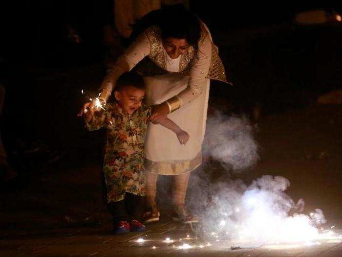 A woman plays with firecrackers with her son to celebrate Diwali, the Hindu festival of lights, in Mumbai, India on Sunday.