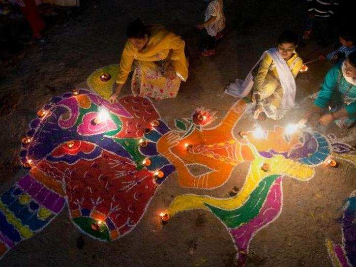 A family from the Hindu community light fireworks as they sit next to a traditional artwork outside their house while celebrating the Diwali festival, in Karachi, Pakistan.