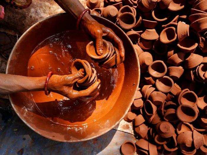 A woman colors earthen lamps for sale ahead of the Hindu festival of Diwali in Mumbai, India.