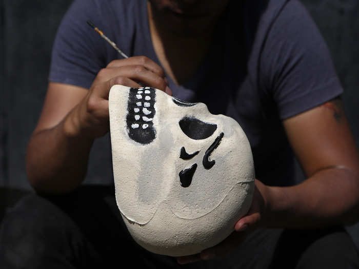 Below, a man painted a Styrofoam skull for an arts competition as part of the parade.