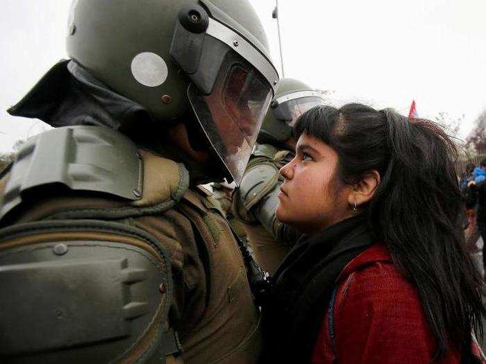 A demonstrator looks at a riot policeman during a protest marking the country