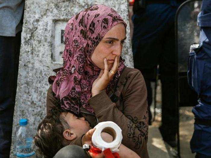 A mother holds her child after migrants and refugees tried to open the border fence at a makeshift camp at the Greek-Macedonian border near the village of Idomeni, Greece, on April 7.