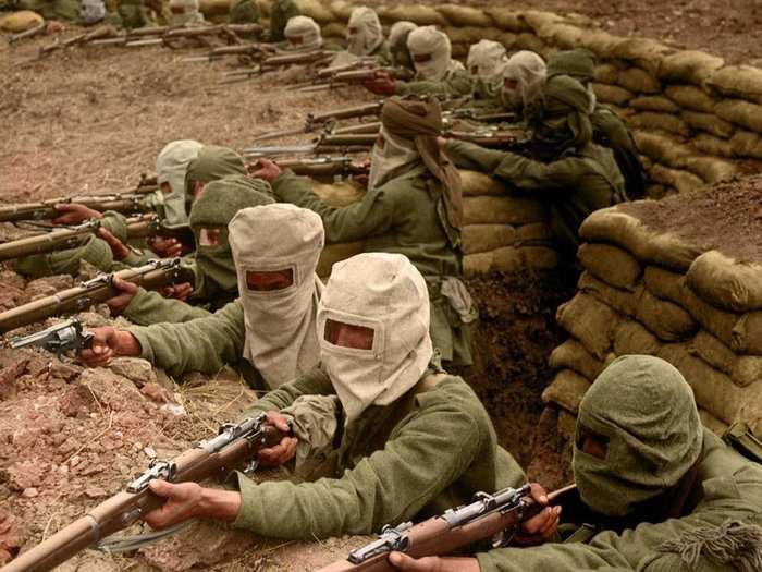 Fearing a gas attack, Indian infantry soldiers don their masks while taking position in a trench.