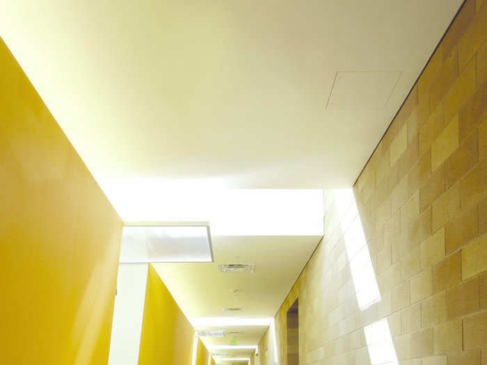 Inside, the building prioritizes ventilation and natural light to create a comfortable environment. The walls are painted bright yellow.