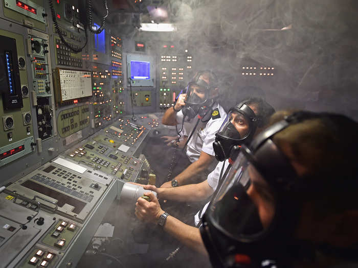 Royal navy personnel responding to a fire in the control room of a Vanguard-class ship simulator.