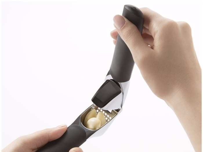 A handheld garlic crusher.