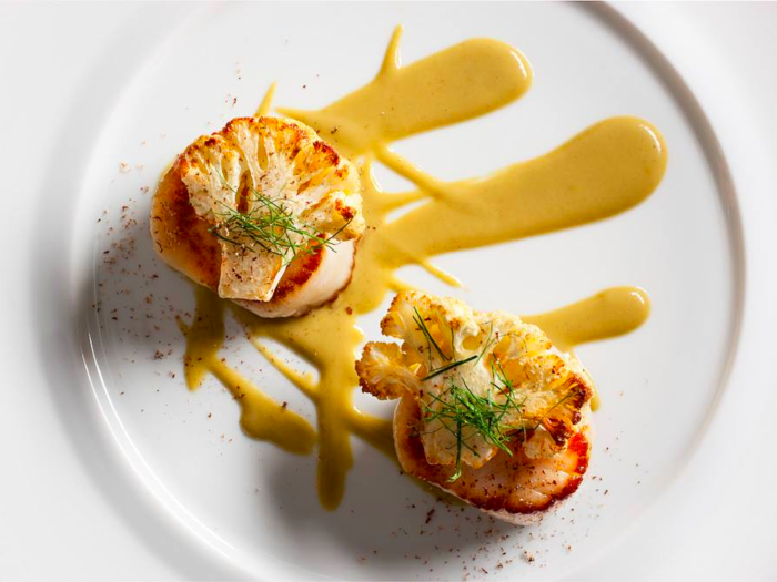 In the next course, diver sea scallops are made with caramelized cauliflower and a caper-raisin emulsion.