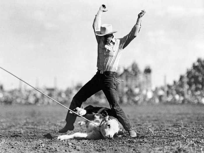 North Dakota, 1950: "Time!" a cowboy signals with upraised arms, having just completed his halfhitch knot at the North Dakota state calf-roping championship in Dickinson.