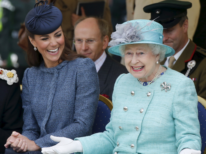 Catherine, Duchess of Cambridge, laughs as Queen Elizabeth gestures while they watch a children