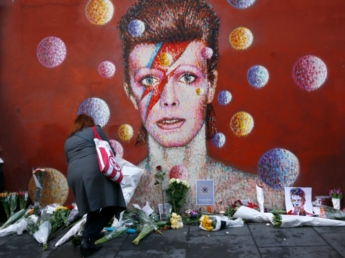 A woman leaves a bouquet at a mural of David Bowie in Brixton, south London.