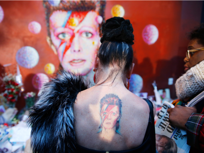 A woman with a Ziggy Stardust tattoo visits a mural of David Bowie in Brixton, south London. The pop legend passed away in January.