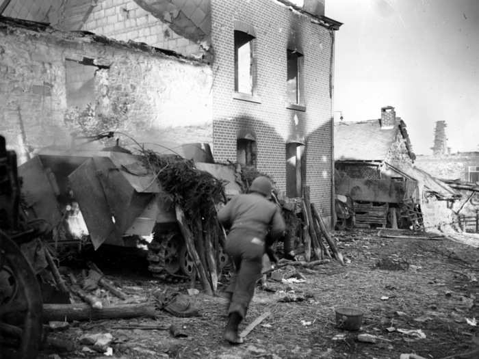 A soldier runs past a burning German half-track in the recaptured town of La Glieze, Belgium, in 1944 during the Battle of the Bulge in World War II.