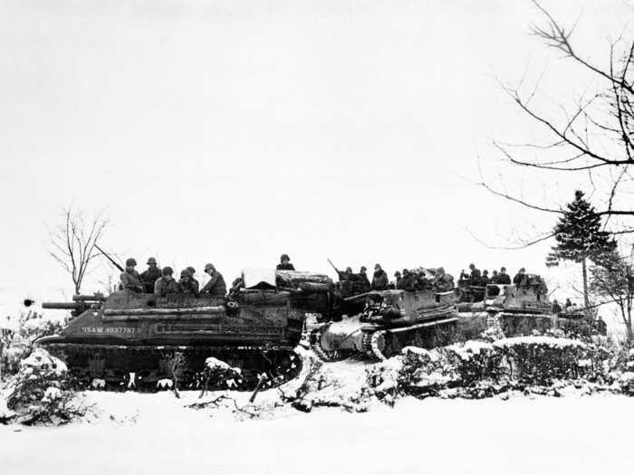 American tanks and armored gun carriers drive over snow-covered terrain toward Samree, Belgium, December 1944, during World War II.