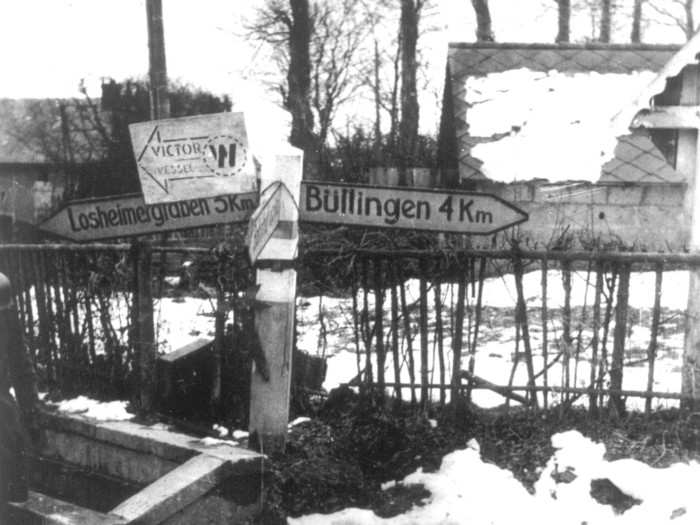 This captured German photo shows two dead American soldiers, stripped of all their equipment, as they lie face down in the slush of a crossroad in an unknown village near Buellingen, in the Province Liege in Belgium, in December 1945.