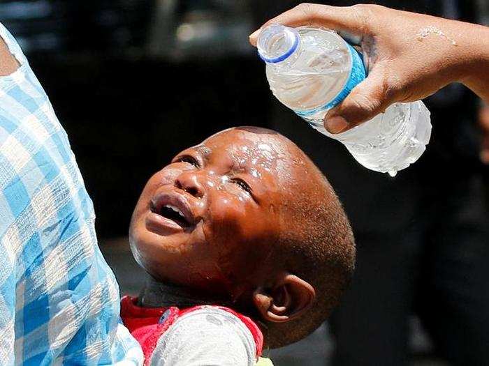 A woman pours water over a child affected by teargas after clashes between police and street vendors in central Harare, Zimbabwe, on September 27.