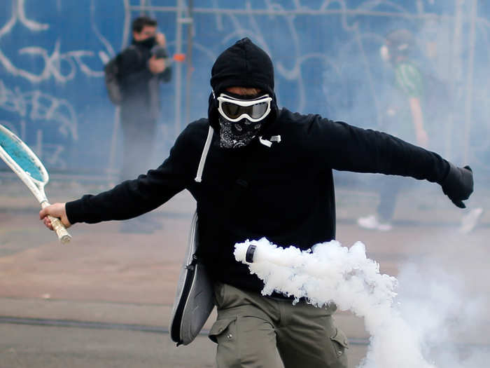 A protestor uses a tennis racket to bounce a tear gas canister during a demonstration to protest the government