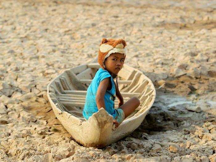 A girl sits on a boat at a dried-up pond at the drought-hit Kandal province in Cambodia on May 13.
