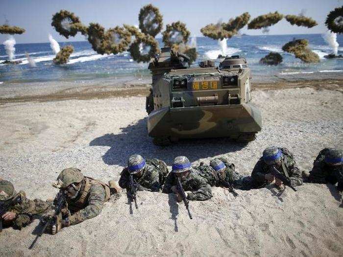 South Korean (blue headbands) and US Marines take positions as amphibious assault vehicles of the South Korean Marine Corps fire smoke bombs during a US-South Korea joint landing operation drill in Pohang, South Korea, on March 12.