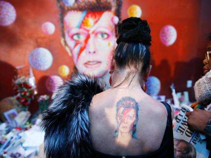 A woman with a Ziggy Stardust tattoo visits a mural of David Bowie in Brixton, south London, the day after his death, on January 11.